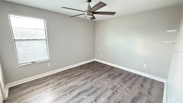 a view of empty room with wooden floor and fan