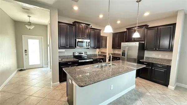 a kitchen with stainless steel appliances granite countertop a refrigerator a stove a sink and a microwave