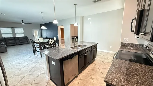 a kitchen with stainless steel appliances granite countertop a sink a stove and a wooden floors