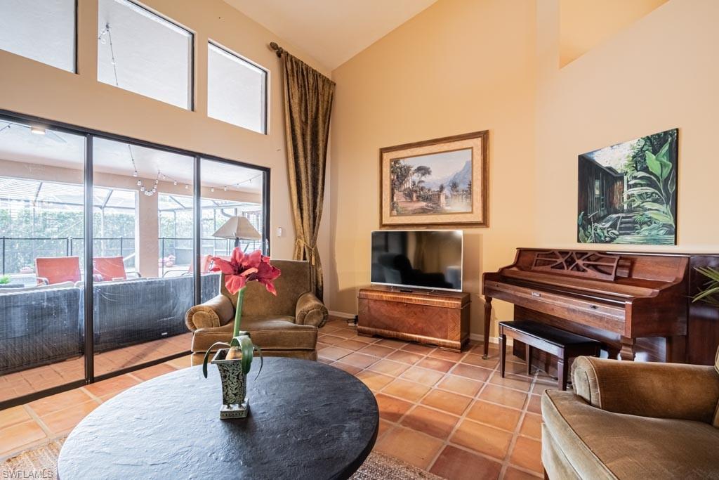 2209 Pinewoods Circle Naples, FL 34105 - Photo 8 of 46 a living room with furniture a piano and a flat screen tv
