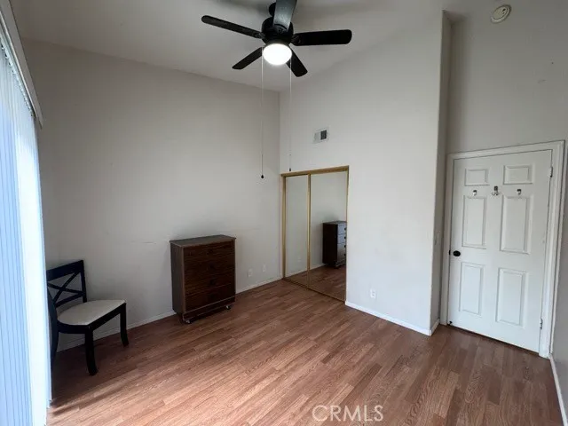 an empty room with wooden floor a ceiling fan and windows