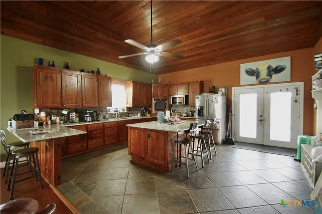 a large kitchen with kitchen island granite countertop a sink counter and chairs