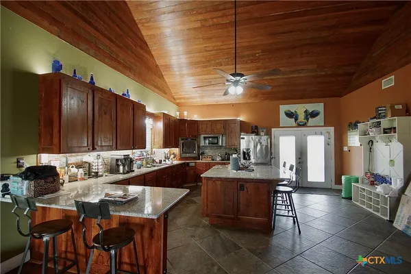 a kitchen with a dining table chairs stainless steel appliances and cabinets