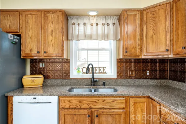 a kitchen with granite countertop a sink a stove and cabinets