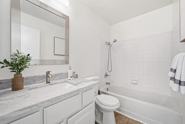 a bathroom with a sink a toilet a mirror a bathtub and shower