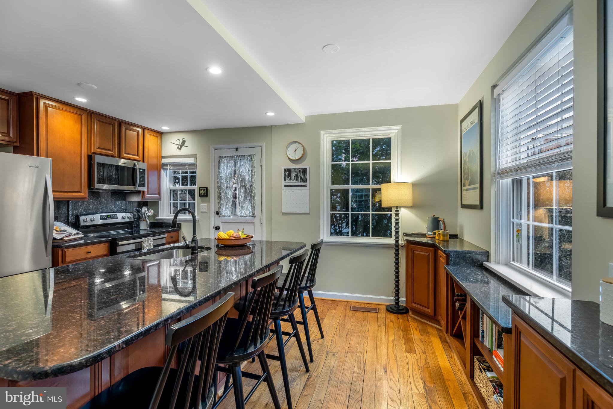 4225 32nd Road South Arlington, VA 22206 - Photo 14 of 36 a kitchen with stainless steel appliances granite countertop a stove top oven a refrigerator a sink a dining table and chairs with wooden floor
