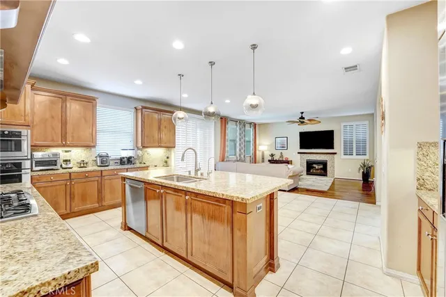 a large kitchen with stainless steel appliances kitchen island granite countertop a sink counter space and a view of living room