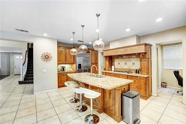 a kitchen with stainless steel appliances kitchen island granite countertop a sink and a refrigerator