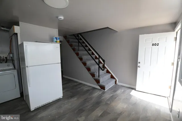 a view of a kitchen with refrigerator and wooden floor