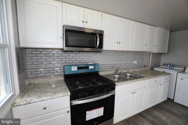 a kitchen with granite countertop white cabinets stainless steel appliances and a sink