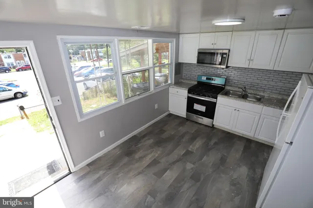 a kitchen with granite countertop a refrigerator a sink a stove a microwave a counter space and cabinets