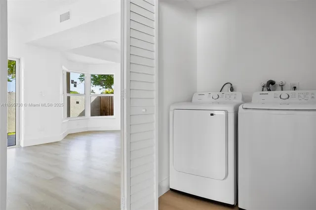 a view of a hallway to a room with wooden floor and cabinet