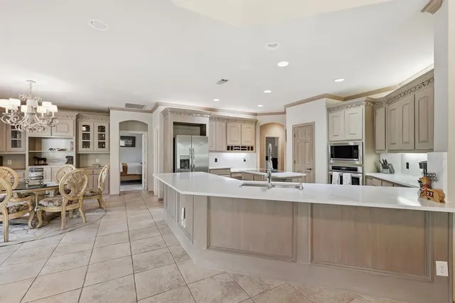 a large white kitchen with cabinets and chairs