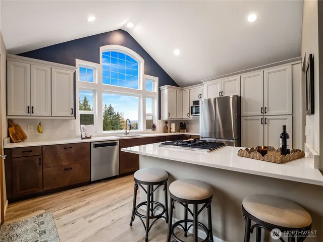 a kitchen with stainless steel appliances a table chairs refrigerator and cabinets