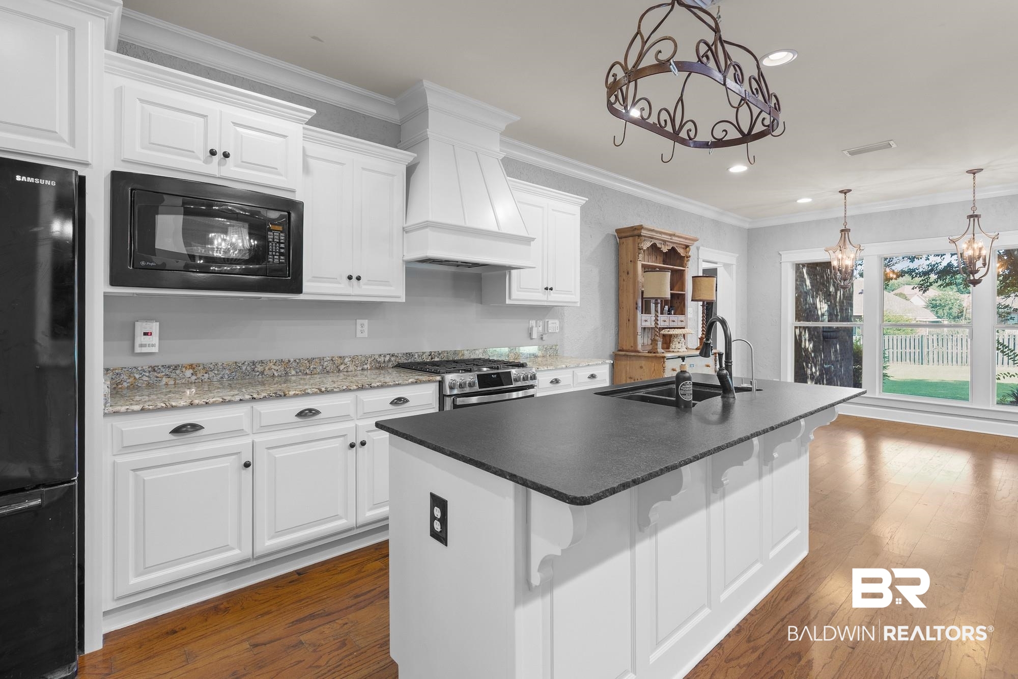 11261 Halcyon Loop Daphne, AL 36526 - Photo 11 of 41 Kitchen featuring white cabinetry, granite countertops, a central island with a dark solid surface countertop and undermount sink, a built-in microwave, and wood-finish flooring