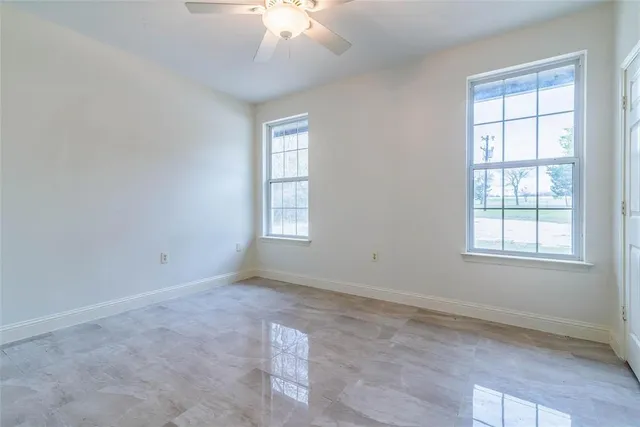 an empty room with windows and chandelier fan