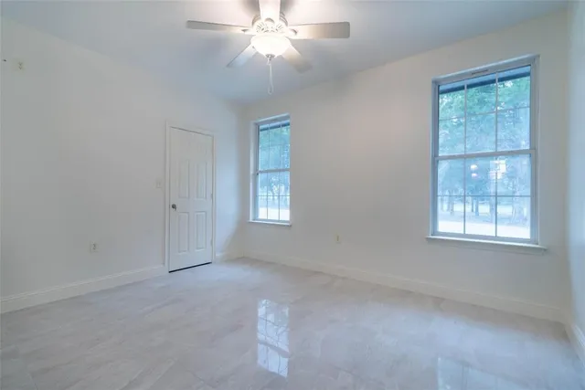 an empty room with windows and fan