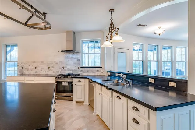a kitchen with stainless steel appliances granite countertop a sink a stove and a wooden cabinets