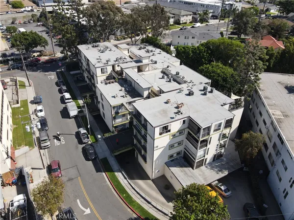 an aerial view of a residential apartment building with a yard and parking spaces