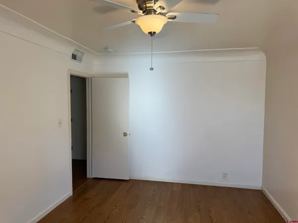 a view of a room with wooden floor and a ceiling fan