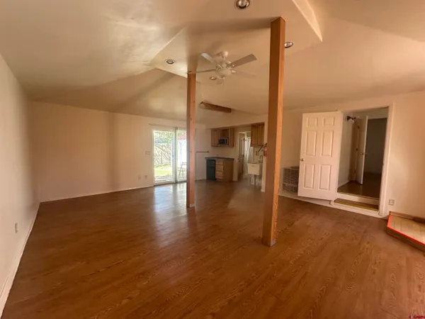 a view of an empty room with wooden floor and a window