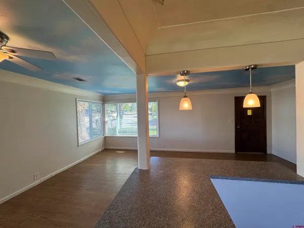a view of an empty room with window and wooden floor