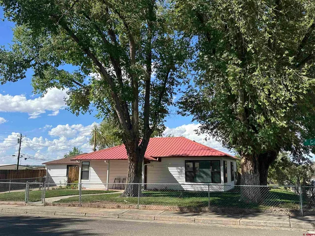 a front view of a house with yard and tree