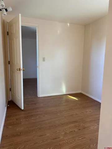 a view of an empty room with wooden floor and closet