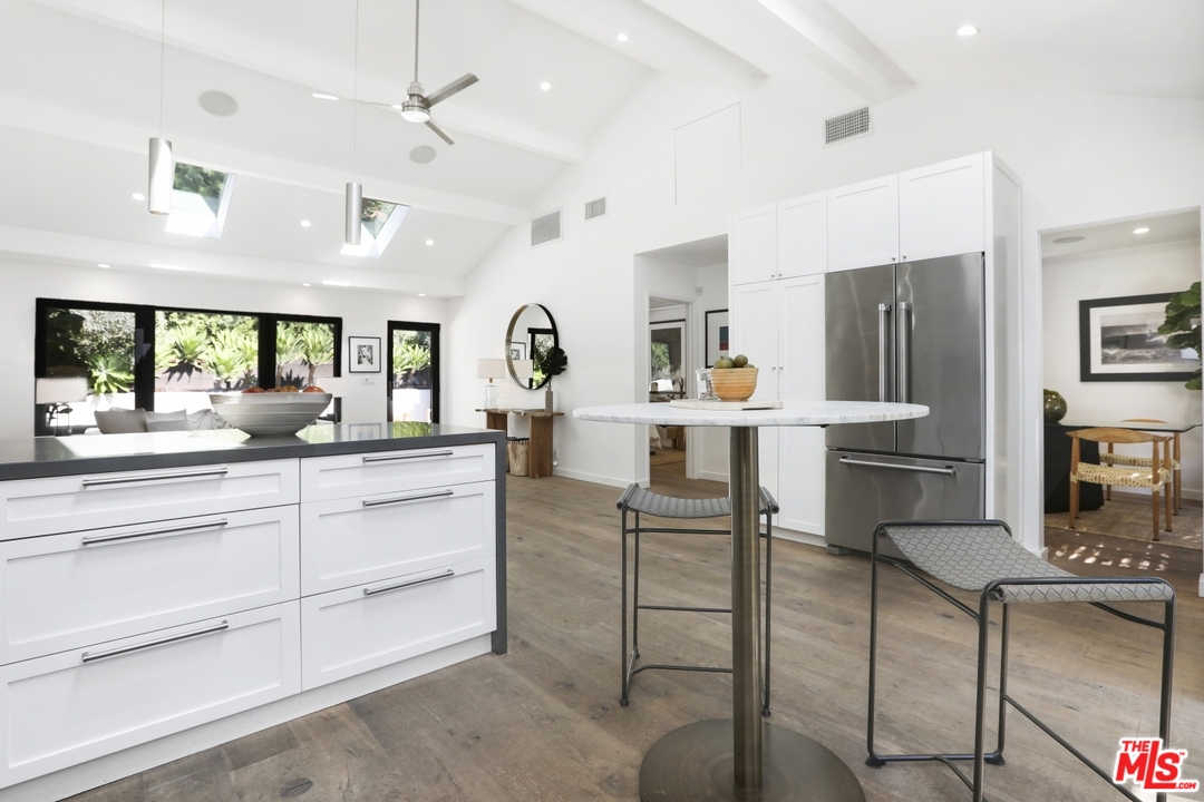 2425 Rinconia Drive Los Angeles, CA 90068 - Photo 11 of 32 a kitchen with stainless steel appliances kitchen island granite countertop a table chairs refrigerator and sink
