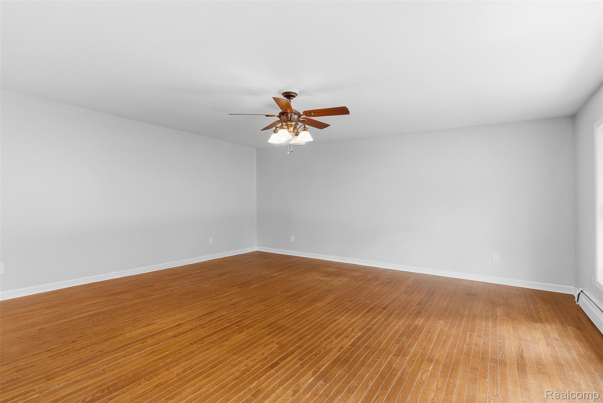 9200 Hickory Ridge Road Holly, MI 48442 - Photo 8 of 33 Spacious room featuring wood-finish flooring, white walls, and a ceiling fan with integrated lighting