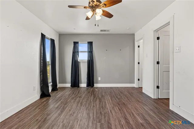 an empty room with wooden floor and a ceiling fan