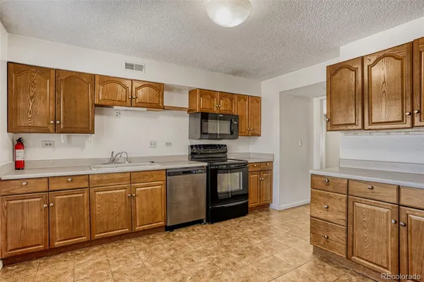 a kitchen with stainless steel appliances granite countertop a stove top oven a sink and dishwasher a oven with wooden cabinets