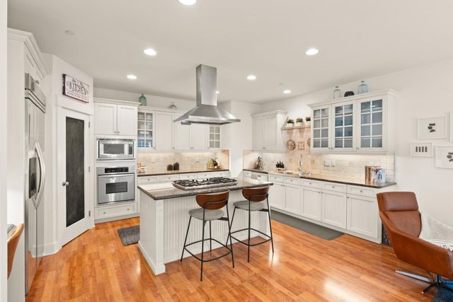 a kitchen with stainless steel appliances a dining table chairs sink and wooden cabinets