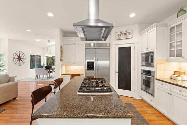 a large kitchen with stainless steel appliances granite countertop a stove a sink dishwasher and a refrigerator with wooden floor