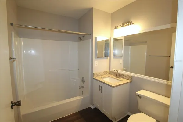 a bathroom with a granite countertop sink mirror vanity and toilet