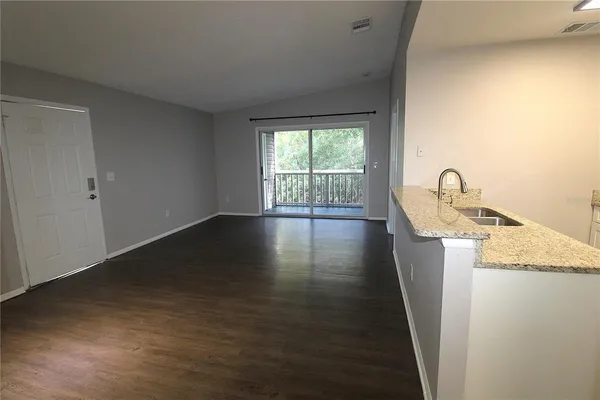 a kitchen with granite countertop a sink a stove cabinets and wooden floor