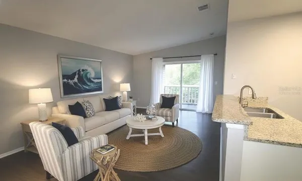 a living room with furniture a large window and wooden floor