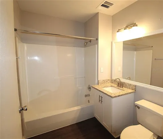 a bathroom with a granite countertop sink toilet and shower