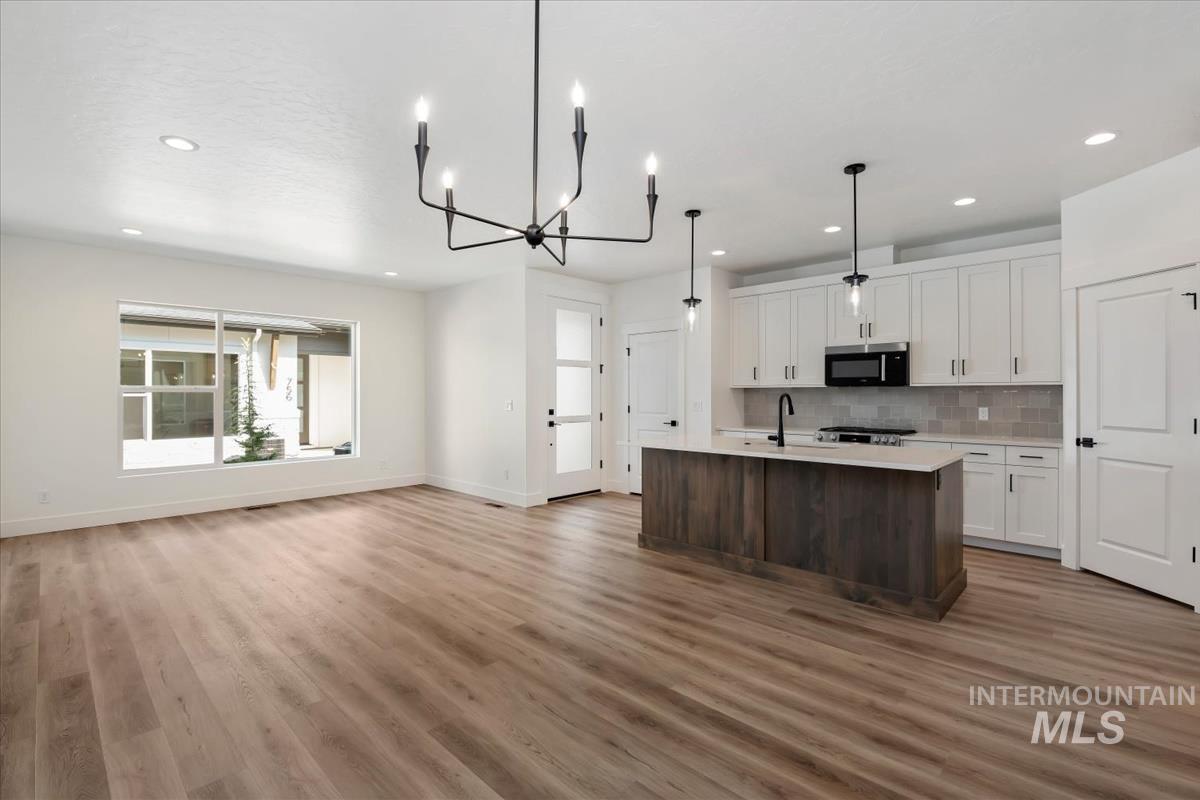 768 South Calhoun Lane Star, ID 83669 - Photo 8 of 36 Open-concept living area featuring wood-finish flooring, a contemporary black chandelier, recessed lighting, and a kitchen island with pendant lighting