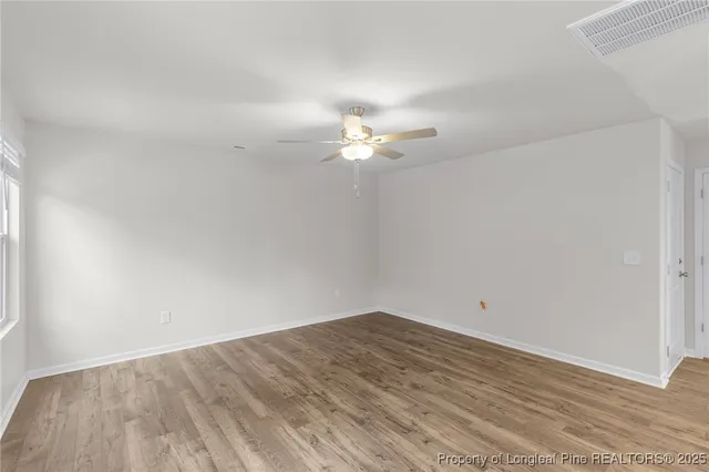 a view of a room with wooden floor and a ceiling fan