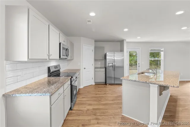 a kitchen with stainless steel appliances granite countertop a refrigerator a sink and a stove