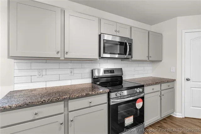 a kitchen with granite countertop white cabinets stainless steel appliances and a sink
