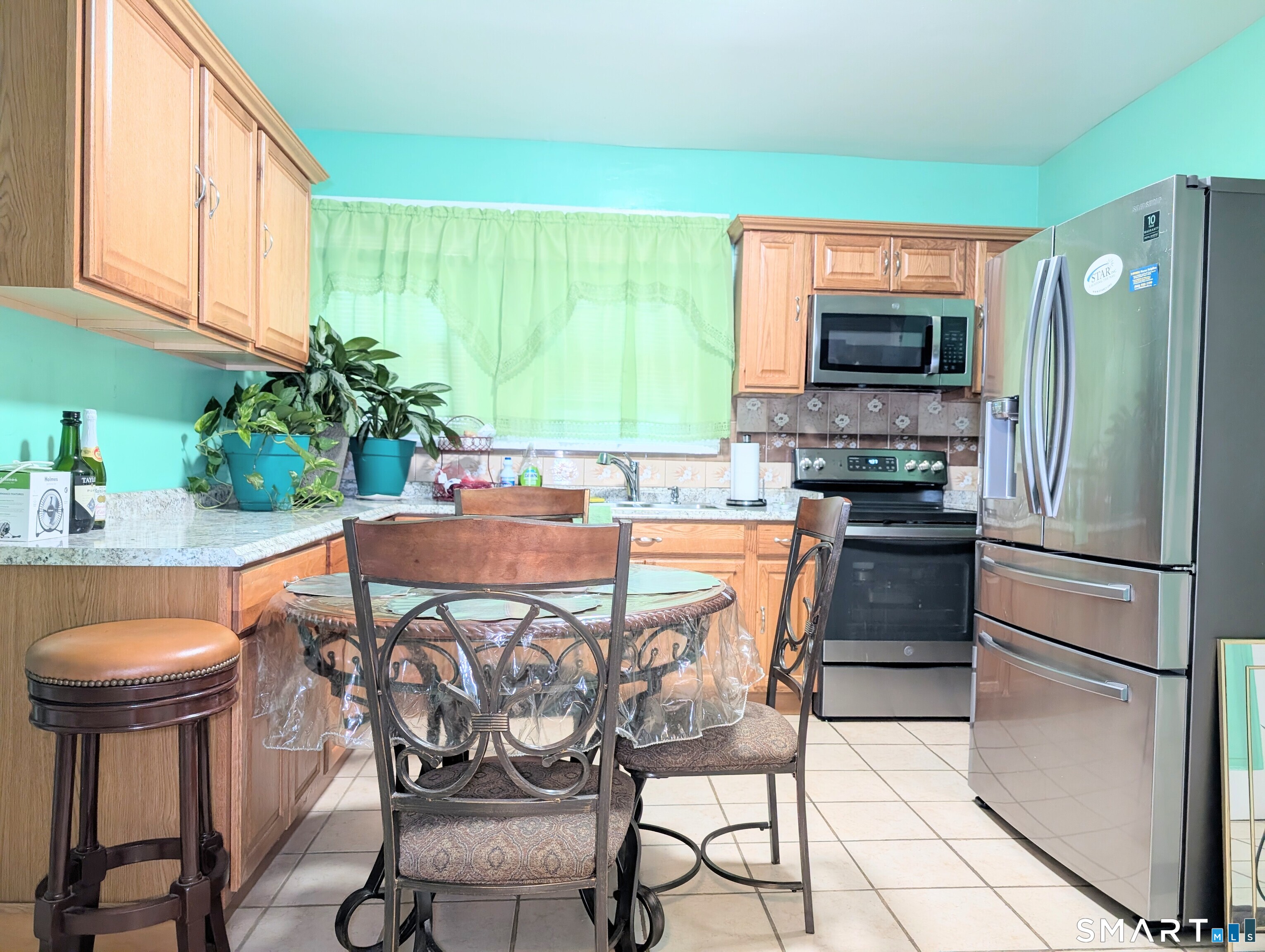 454 Pembroke Street Bridgeport, CT 06608 - Photo 10 of 40 a kitchen with stainless steel appliances a dining table chairs microwave and sink