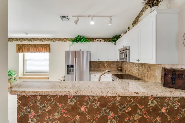 a kitchen with stainless steel appliances granite countertop a sink refrigerator and microwave