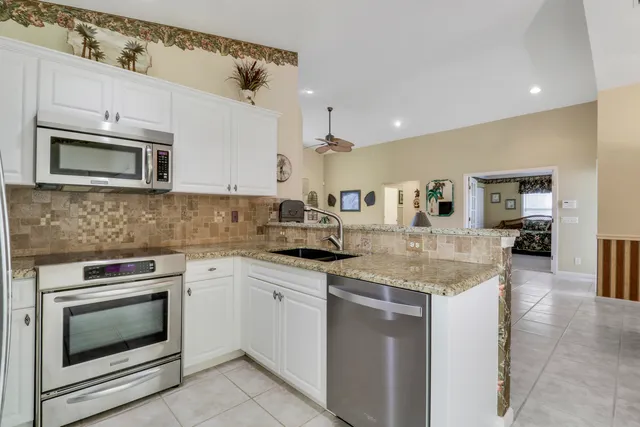 a kitchen with granite countertop a refrigerator stove and microwave