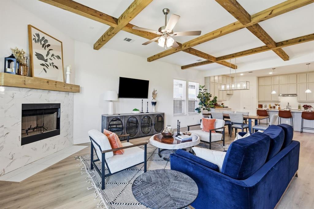4017 Eagles Bluff Road Midlothian, TX 76065 - Photo 25 of 38 Living area featuring exposed wooden beams, a gas fireplace with a light-toned surround, wood-finish flooring, and multiple windows