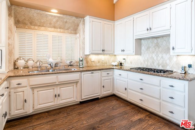 a kitchen with granite countertop white cabinets and stainless steel appliances