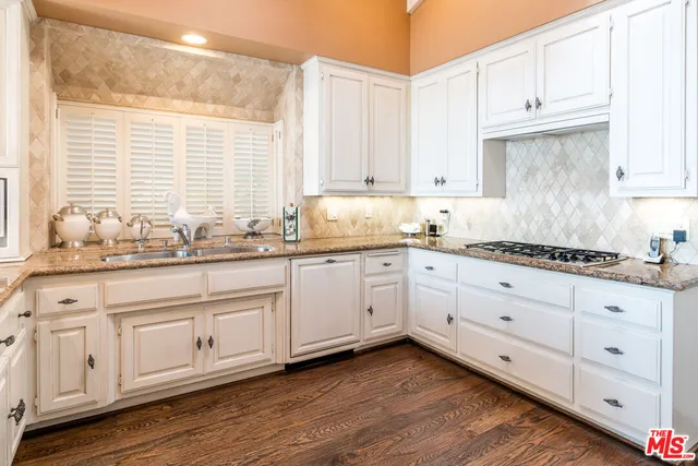 a kitchen with granite countertop white cabinets and stainless steel appliances