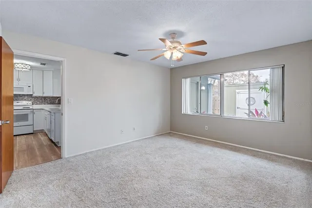 an empty room with windows and ceiling fan