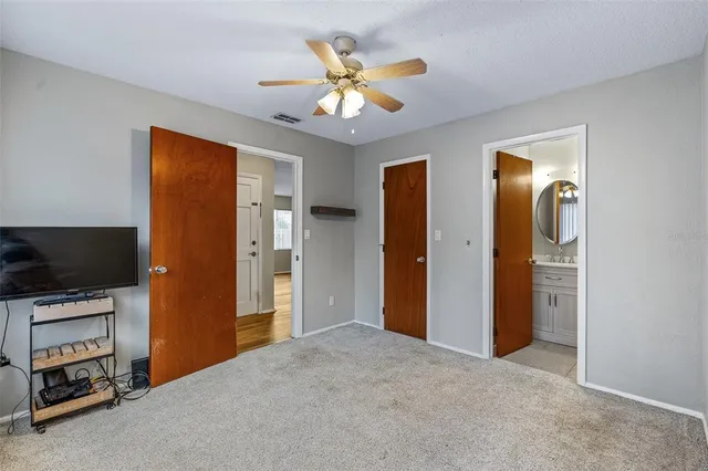 a view of an empty room with a fireplace and a ceiling fan